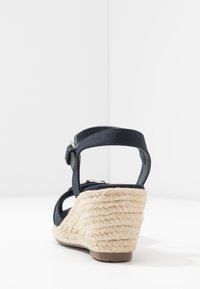 Námořnické plátěné sandály na klínu s pletenou juty podešví. Obsahují nastavitelný popruh a otevřenou špičku, která ukazuje texturovaný povrch a pevnou konstrukci.