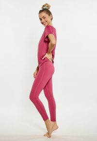 Rózsaszín sport szett, amely egy rövidujjú, laza szabású felsőből és testhez simuló leggingsből áll. Az anyag sima, rugalmas, látható varratokkal.