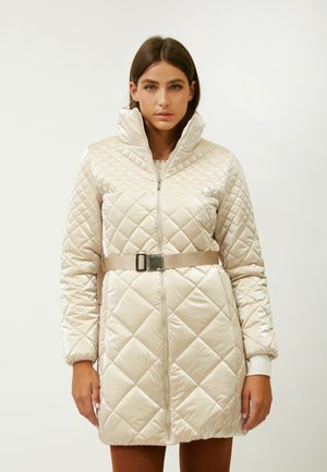 Giubbotto imbottito trapuntato in beige chiaro, con un colletto alto, zip a tutta lunghezza e vita aderente con fibbia metallica. Design testurizzato.