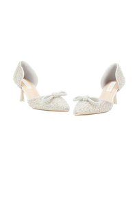 Tacones adornados con cristales, con punta afilada, tejido suave de color blanco y un pequeño lazo como acento. Presentan un tacón delgado y una superficie texturizada.