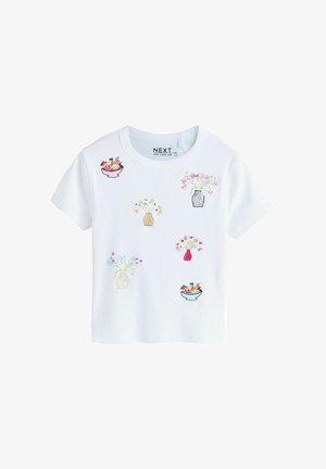 Hvid kortærmet T-shirt med farverige broderede blomster- og frugtskålmotiver spredt foran.