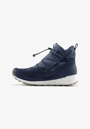 Scarpa alla caviglia di colore blu navy con tomaia in tessuto testurizzato, lacci elastici e suola intermedia bianca maculata. Presenta una punta e un tallone rinforzati.