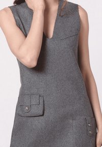 Vestido sin mangas gris con escote en V, que presenta bolsillos de parche en el frente y acentos de botones. Textura suave y diseño minimalista.