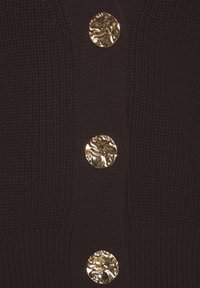 Braune Strickjacke mit drei strukturierten, runden goldenen Knöpfen, die der Gesamtgestaltung Dimension und visuelles Interesse verleihen.