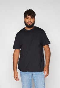 Schwarzes Baumwoll-T-Shirt mit kurzen Ärmeln und Rundhalsausschnitt, kombiniert mit hellblauen, ausgefransten Jeans. Einfaches und lässiges Design.