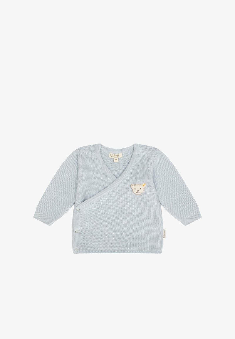 Světle modrý pletený kardigan s V-výstřihem, dlouhými rukávy a bočními knoflíky. Na přední straně se nachází aplikace medvídka a texturovaná tkanina.