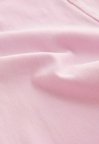 Tela de color rosa claro con una textura suave, que muestra un fino patrón de tejido diagonal y una caída ligera. No hay detalles o adornos notables visibles.