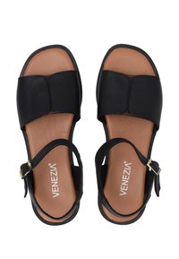 Zwarte leren sandalen met een platte zool, voorzien van een brede voorband en een verstelbare enkelband met een gouden gesp. Bruin voetbed.
