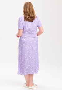 Fialové midi šaty s krátkým rukávem, zdobené vzorem listů v světle krémové barvě. Měkká, lehká tkanina s volným střihem.