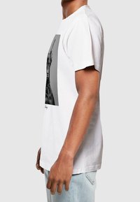 Bílá bavlněná trička s černobílým grafickým potiskem na přední straně, krátkými rukávy a kulatým výstřihem.