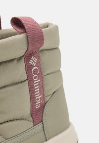 Columbia pilka avalynė su paminkštintu viršumi, tekstūruota rožinė kilpa ir šoniniu logotipu, su tvirta, formuota balta pada.