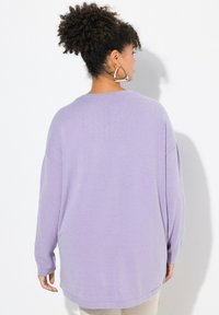 Maglione oversize lilla con maniche lunghe e scollatura rotonda. Texture morbida con una vestibilità comoda e spacchi laterali all'orlo per un movimento aggiuntivo.