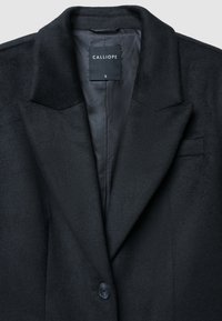 Blazer in lana nera con rever, chiusura a un bottone e fodera interna liscia. L'etichetta indica "CALLIOPE" con taglia "S."