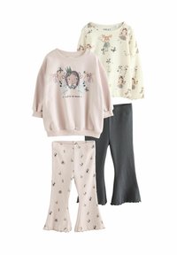 Zwei langärmelige Blusen in Hellrosa und Creme, die verspielte Grafiken zeigen, kombiniert mit hellrosa und dunkelgrauen Schlagleggings mit Blumenmustern.