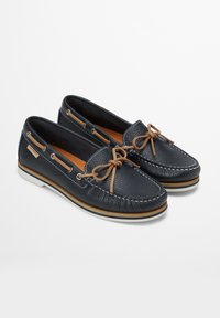 Marineblaue Lederbootsschuhe mit strukturiertem Finish, weißen Nähten und einer kontrastierenden hellbraunen Schnürung. Mit einer weißen Gummisohle.