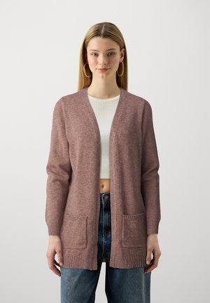 Rosa cardigan med v-hals, lange ermer, ribbede mansjetter og to frontlommer. Brukt over en hvit topp og kombinert med høyhåndte jeans.