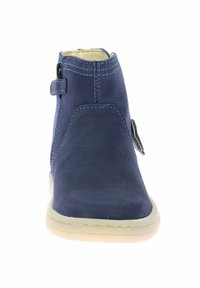 Bottine en cuir bleu marine avec un bout rond, une fermeture éclair sur le côté et des coutures beiges. La semelle en caoutchouc offre stabilité et traction.