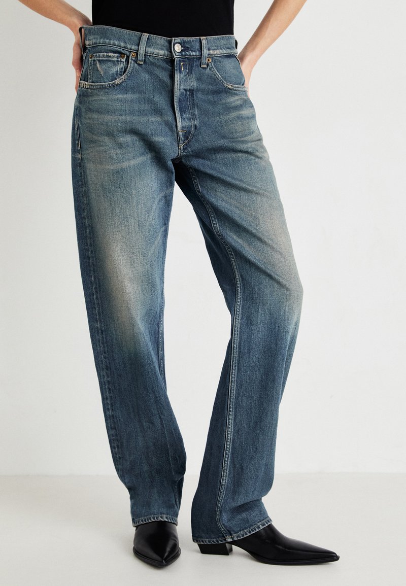 Lys blå denimjeans med rette ben, fem-lomme-design og subtil fading, sammen med svarte spisse boots.