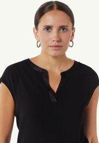 Zwart T-shirt met korte mouwen en een V-hals afgewerkt met satijn, met een gladde textuur en een ontspannen pasvorm. Geen patronen of opvallende hardware details aanwezig.