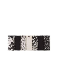 Un bandeau en tissu noir et blanc présentant des sections alternées de motifs floraux et de couleurs unies, agrémenté de nœuds décoratifs.