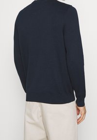 Marineblauwe trui gemaakt van gebreide stof, met een ronde hals en lange mouwen, voorzien van een geribde zoom en manchetten, met een gladde textuur.