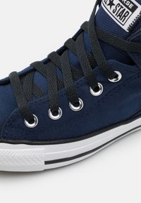 Marinblå canvas-sneakers med svarta snören, silverfärgade ögla och vit sula. Tyg med struktur och kontrasterande gummitådetalj.