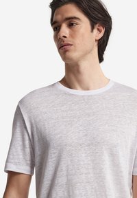 Vit crewneck t-shirt gjord av lätt, andningsbart tyg. Korta ärmar, avspänt snitt och subtil textur med en mjuk finish.