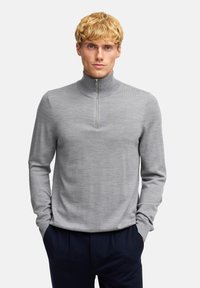 Grauer Pullover mit Reißverschluss am Hals, gefertigt aus einem glatten, leichten Stoff. Mit langen Ärmeln und einer figurbetonten Passform für eine schlanke Silhouette.