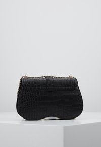 Czarna torebka z sztucznej skóry w kroku krokodyla o gładkiej fakturze, zaokrąglonym kształcie i złotej łańcuszkowej rączce, z klapą zamykającą.