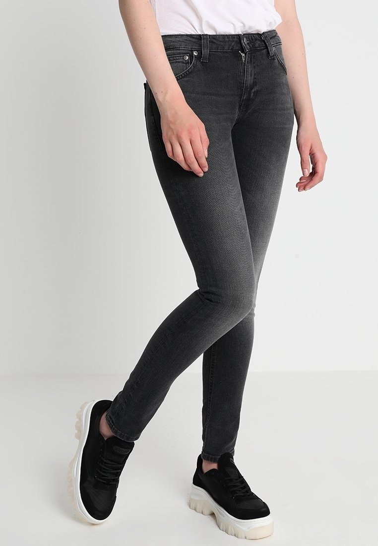 Svarta slim-fit jeans med blekning, fem fickor och dragkedja. Bärs med svarta sneakers med vit sula.