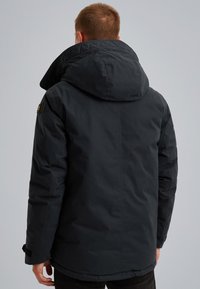 Temno siva puhovka z velikim kapuco, teksturirano blago in stranskimi žepi. Ima šive in nastavljive rokave.