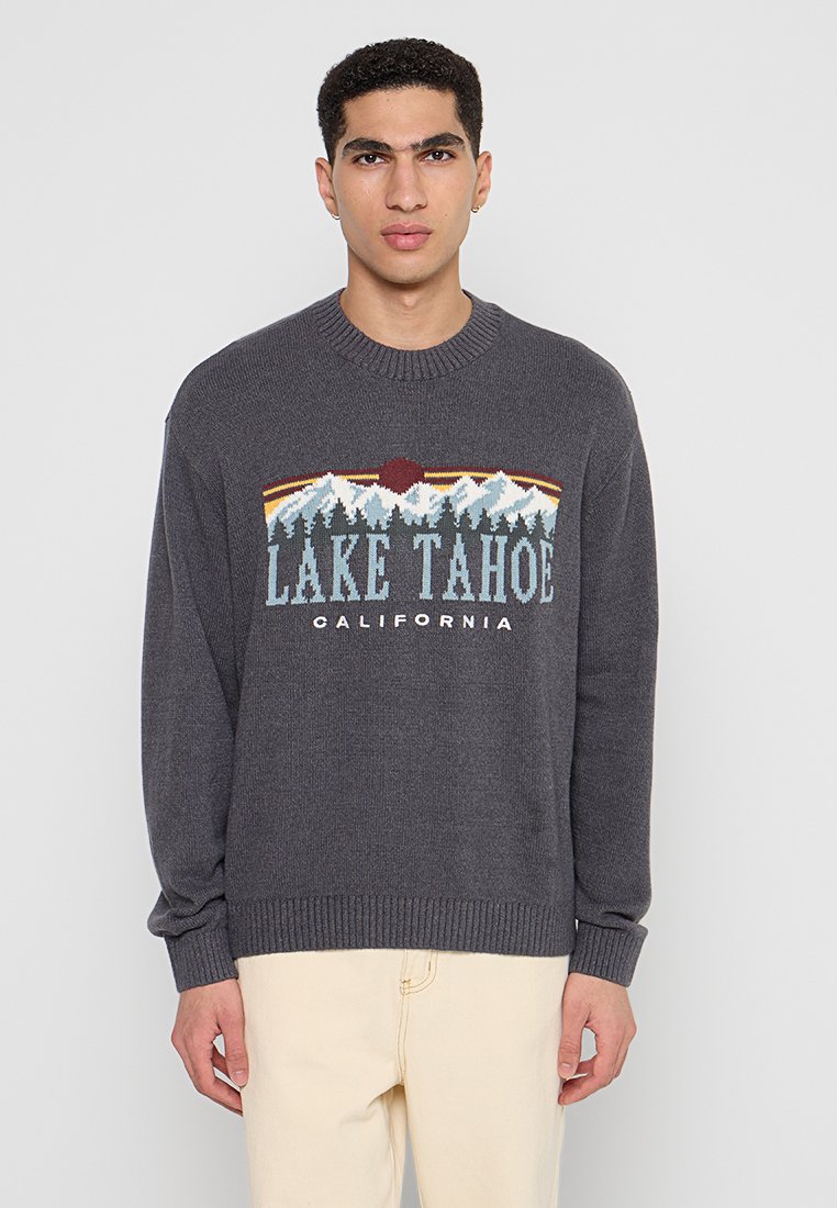 Grau gestrickter Pullover mit einem Grafikmuster von Bergen und "LAKE TAHOE CALIFORNIA" in Blau und Weiß, mit einem gerippten Kragen und Bündchen.