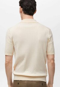 Short-sleeve ribbed knit polo in light beige with a classic collar and a fitted silhouette, featuring a subtle texture and clean finish.