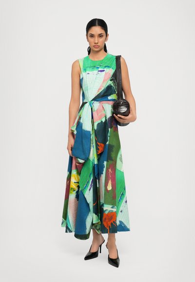 Dress featuring a multicolored abstract print in greens, blues, and pinks, with a draped design and tied waist; paired with a black circular bag.