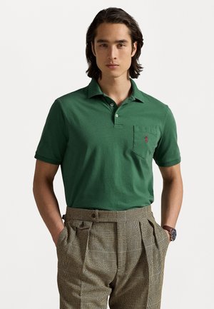 Roheline lühikeste varrukatega polo särk kraega ja väikese rinnahoinikuga, klassikalise lõikega ja logodetailiga. Kombineeritud ruuduliste pükstega.