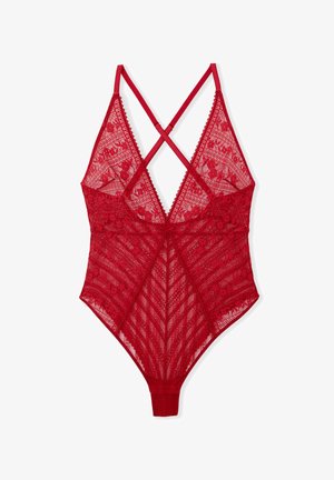 Body en dentelle rouge avec motifs floraux, bretelles croisées, bords festonnés, et une coupe ajustée mettant en valeur une texture transparente.