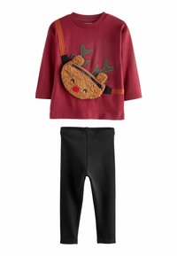 Chemise rouge à manches longues avec une poche en renne en peluche et des leggings noirs. La poche est dotée d'une fermeture éclair, de cornes et d'un nez rouge. Texture douce.