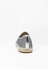 Ballerines espadrilles avec un embout de talon métallique argenté, un dessus en tissu pailleté gris et une semelle en jute tressé pour la texture et la flexibilité.