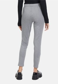 Šedé legíny se slim fit, vyrobené z měkké látky. Mají vysoký pas a jemné švy. Doplňuje je černé platformové boty.