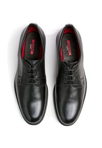 Zwarte leren schoenen met een gladde textuur, een ronde neus en een vetersluiting. Het interieur heeft rode accenten en een gewatteerde binnenzool met logo.