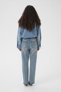 Svetlomodrá rifľová bunda s krátkym strihom, skombinovaná s voľnými svetlomodrými rifľami. Obe majú klasické prešívanie a zadné vrecká.