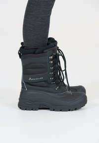 Stivali invernali neri isolati con gambale alto, suola in gomma, occhielli in metallo e design con lacci. Presenta un bordo imbottito e dettagli testurizzati.