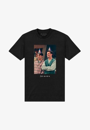 Maglietta nera in cotone con una grafica che raffigura due personaggi che indossano cappelli da festa, con il testo "F.R.I.E.N.D.S" sotto l'immagine.