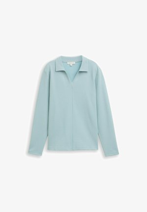 Jasnoniebieska bluzka z długim rękawem o luźnym kroju, z dekoltem w serek i kołnierzykiem. Teksturowana tkanina i minimalne szwy.