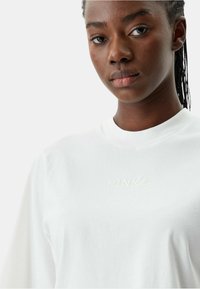 Witte katoenen blouse met lange mouwen, voorzien van een ronde halslijn en subtiele "PINKO" borduring in het midden. Gladde textuur en een relaxte pasvorm.
