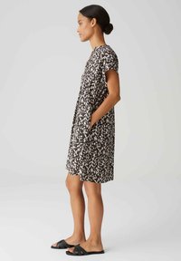 Kurzärmeliges Kleid mit abstraktem Muster in Schwarz und Weiß, aus leichtem Stoff gefertigt, mit seitlichen Taschen und lockerer Passform.