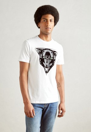Camiseta blanca de algodón que presenta un gráfico de la cara de una pantera negra con ojos verdes, enmarcada dentro de un diseño triangular. Cuello clásico de camiseta.