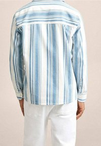 Camisa de algodón con rayas verticales en azul claro y blanco, mangas largas, puños con botones y dobladillo recto. Vista trasera mostrada.