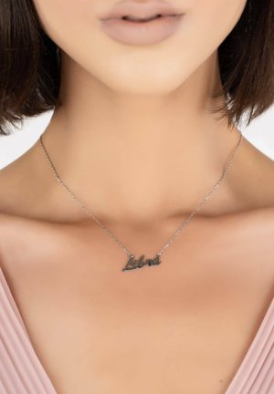 Silver necklace featuring the word "Libra" in a cursive font, suspended from a delicate chain. Smooth texture, subtle shine.