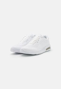 Witte sportschoenen met geperforeerde bovenkant, vetersluiting, gevoerde kraag en luchtkussens in de zool voor extra comfort.